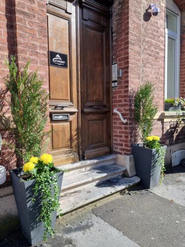 a wooden door of a house with two potted plants at Le Vauban Cambrai in Cambrai