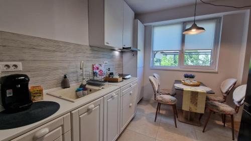 a kitchen with white cabinets and a table and a window at Albert Garden Retreat in Ploieşti