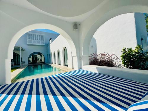 un letto a righe blu e bianche in una stanza con piscina di Charming Luxury Villa Poolside Paradise in Nature a Hammamet