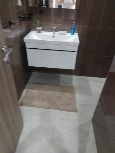 a bathroom with a white sink and a mirror at Magnifique appartement avec vue dégagée, près de l'aéroport et parking privé in Ariana