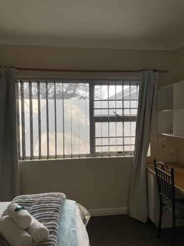 a bedroom with a bed and a large window at 137 High Street Guest House in Grahamstown