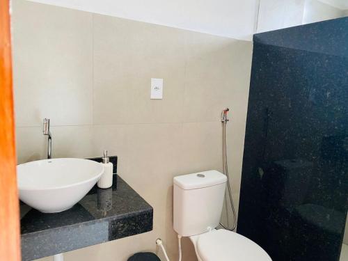 a bathroom with a white toilet and a sink at Recanto do Rancho Trancoso in Porto Seguro