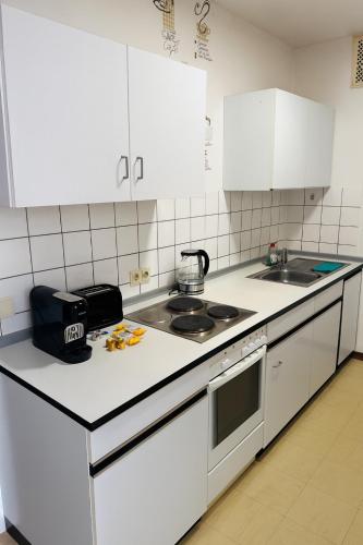 a kitchen with white cabinets and a counter top at Helle 2-Zimmer Erdgeschosswohnung mit Terrasse in Koblenz