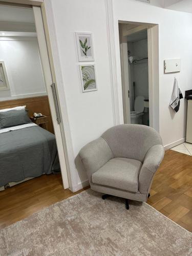 a bedroom with a chair next to a bed at Hotel UH2107 Inter Jardins in Sao Paulo