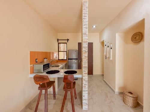 a kitchen with a counter and some chairs in it at Macondo Raíz Holbox in Holbox Island