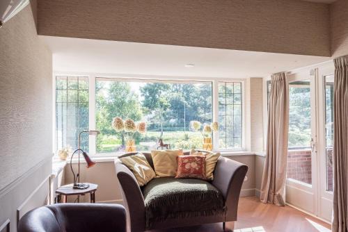 a living room with a chair and a large window at De Kievit in Vogelenzang