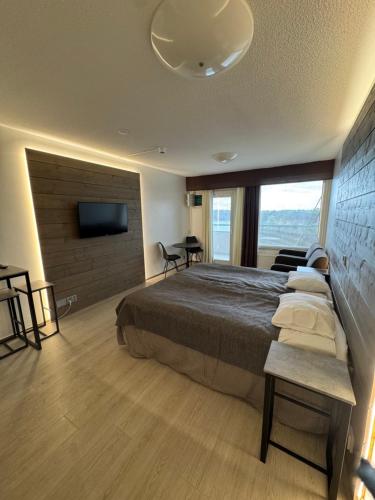 a bedroom with a large bed and a flat screen tv at Hotelli Terme, huone 617 in Ikaalinen