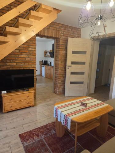 a living room with a wooden table and a tv at Noclegi nad Czarną Orawą in Podwilk