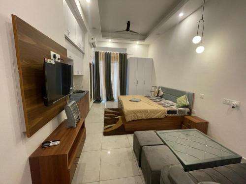 Una pequeña sala de estar con un sofá y un televisor. en Vrinda Homes, en Noida