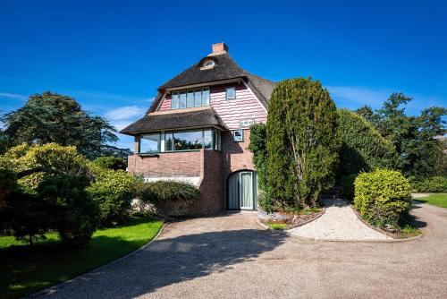 a brick house with a gambrel roof and a driveway at De Kievit in Vogelenzang
