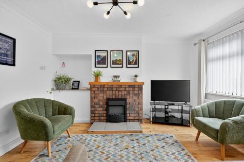 a living room with two chairs and a fireplace at Hillsborough Home from Home, Garden and 2x Parking by StayByNumbers in Hillsborough