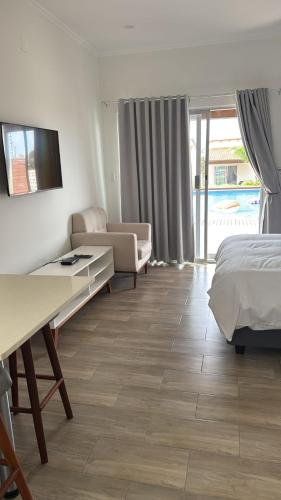 a bedroom with a bed and a desk and a couch at Mar Bela Suites in Ubomo