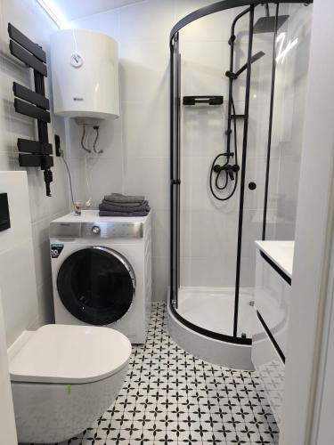 a bathroom with a shower and a washing machine at Belle Apartament in Krapkowice