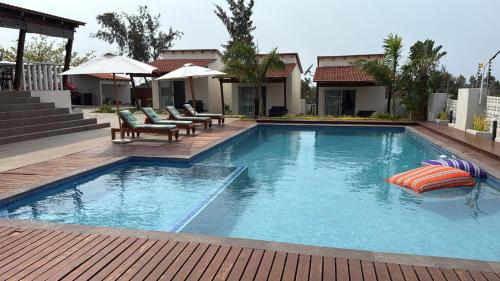 a large swimming pool with chairs and umbrellas at Mar Bela Suites in Ubomo