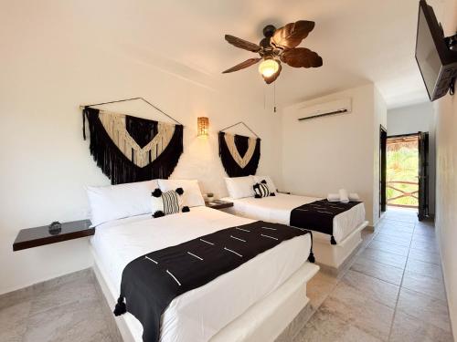 a bedroom with two beds and a ceiling fan at Hotel Esencia Holbox in Holbox Island