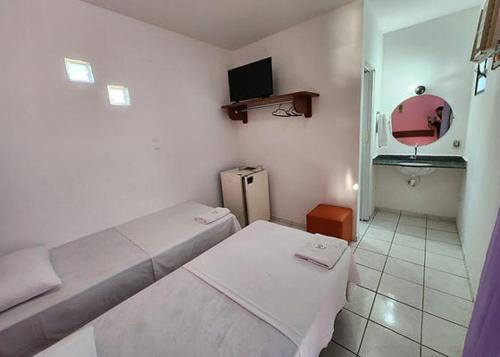 a small room with two beds and a mirror at Pousada Oceano Azul in Guarapari
