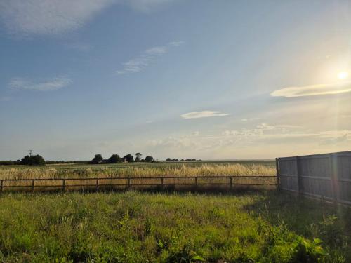 a field with a fence and the sun in the sky at Zoila's Rest - A self-contained studio in Spalding