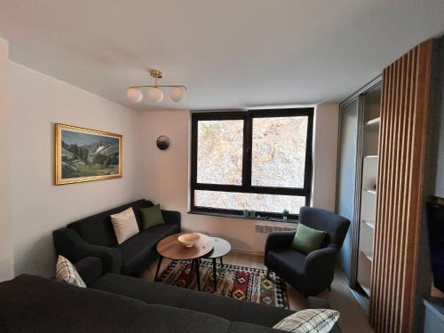 a living room with a couch and two chairs and a window at The New Wild Apartment in Bjelašnica