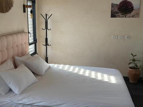 a bed with white sheets and pillows in a room at בסנדלים: חאן בוטיק בגולן in Ma'ale Gamla