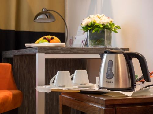 
a coffee pot sitting on top of a table next to a vase at IN Hotel Beograd in Belgrade
