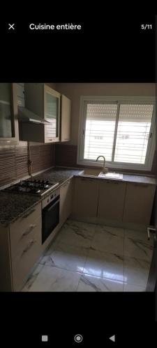 a kitchen with a sink and a stove top oven at Le bon coin in Ariana