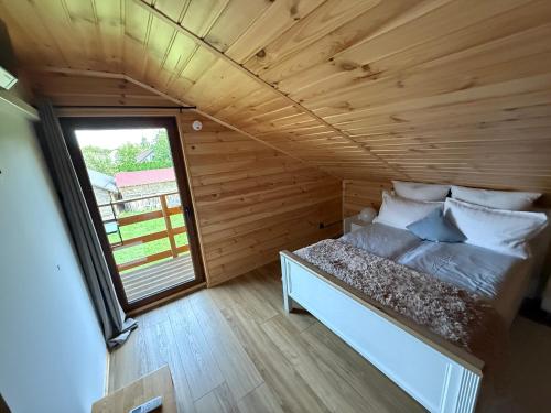 a bed in a small room with a window at Domek pod świerkiem in Tereszpol Zaorenda