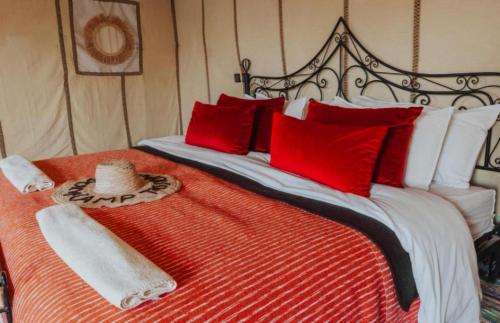 a large bed with red and white pillows at Eternal Luxury Camp in Merzouga