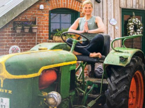 a woman sitting on top of a green tractor at INSEL-LAND-HOTEL MICHAELSEN im November Morgen-Yoga u Sauna inkl in Borkum