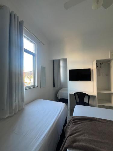 a hotel room with two beds and a window at Hotel Aconchegante in Jequié