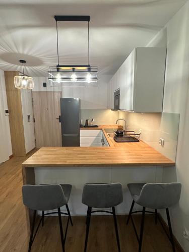 a kitchen with a counter and three chairs in it at Apartament Zielone Tarasy z parkingiem in Bochnia