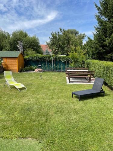 two chairs and a bench in a yard at Két szobás, teraszos, kertes vendégház in Balatonmáriafürdő