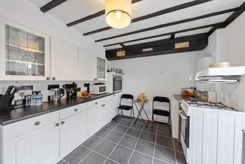 a kitchen with white cabinets and black counter tops at Thorold House Charming house for long stays in Chatham