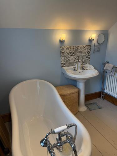 eine Badewanne und ein Waschbecken im Bad in der Unterkunft Buddleia Cottage Trewoon, St Austell in St Austell