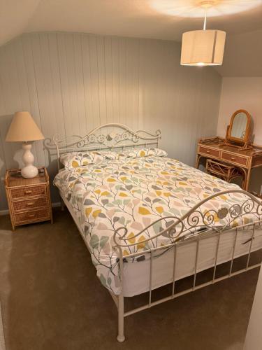 ein Schlafzimmer mit einem Bett, einer Lampe und einem Tisch in der Unterkunft Buddleia Cottage Trewoon, St Austell in St Austell