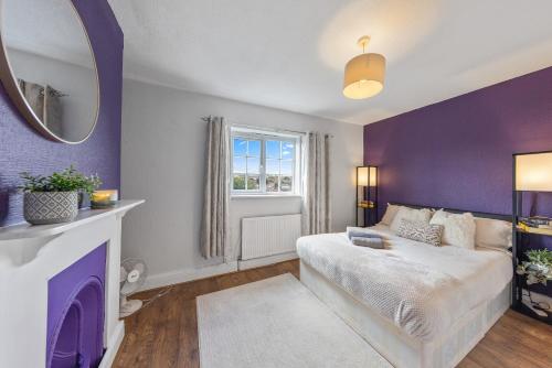 a purple bedroom with a bed and a mirror at Thorold House Charming house for long stays in Chatham