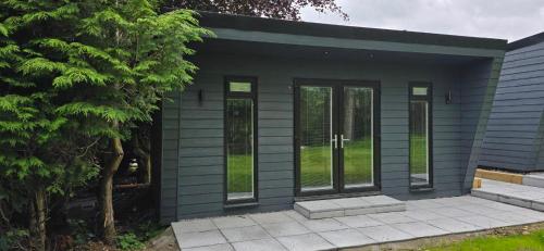 a small blue house with glass doors at Breagha Cabin, Spean Bridge, near Fort William in Spean Bridge