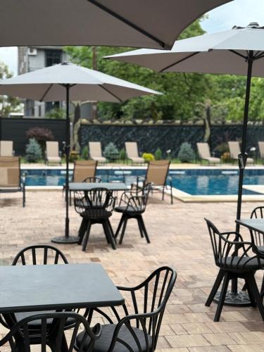 a group of tables and chairs with umbrellas next to a pool at SWEET HOUSE 470 in Kobuleti