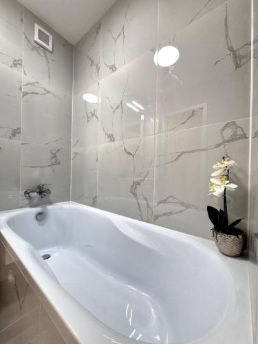 a white bath tub in a bathroom with marble walls at Krásny apartmán v Ružinove in Bratislava