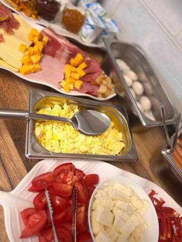 ein Tisch mit Tabletts voller Essen mit Tomaten und Eiern in der Unterkunft Pensiune Agroturistică RAY 