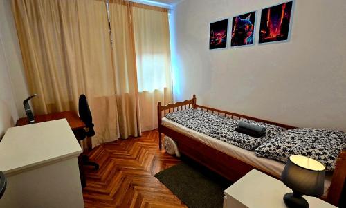 a bedroom with a bed and a desk and a window at Apartman Mik in Daruvar