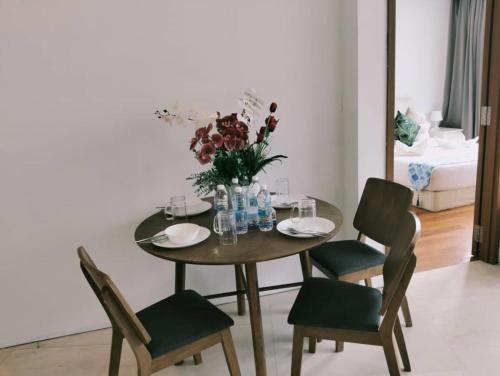 a dining room table with chairs and a vase of flowers at Vortex Suites Dream By KL in Kuala Lumpur