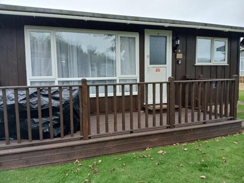 a house with a wooden porch with a fence at Shed No 9 in Colyford