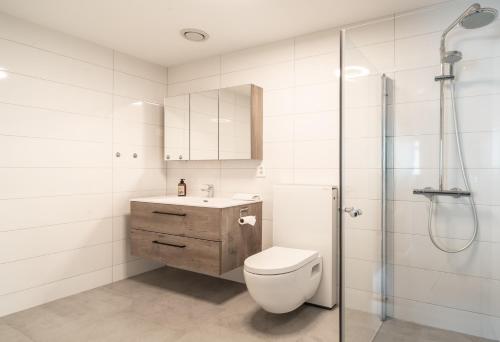 a white bathroom with a toilet and a shower at Staying Apt 4 in Tromsø