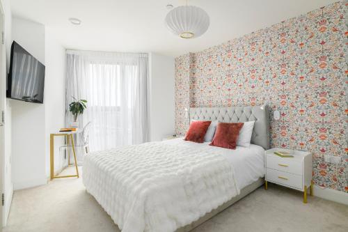 a bedroom with a white bed with red pillows at New in Willesden close to Oxford Str, Wembley, Jubilee line in London
