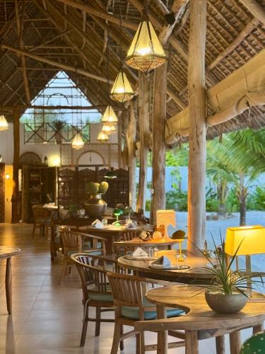 a restaurant with wooden tables and chairs and lights at Infinity Beach Boutique Hotel & SPA in Matemwe