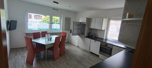 a kitchen with a table and red chairs and a table and a kitchen with at Ferienhaus Falkenstein mit wunderschönem Bergblick in Frauenau