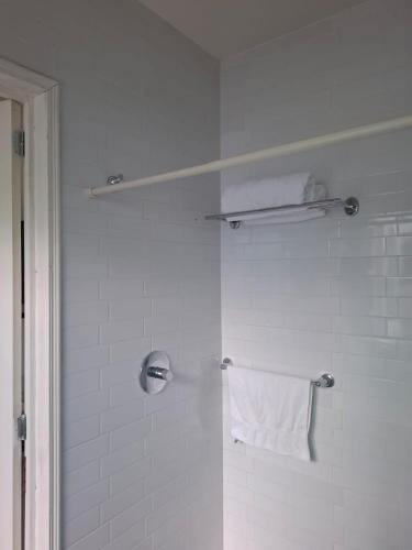 a white bathroom with a shower with a towel at Milenio III B&B in Querétaro