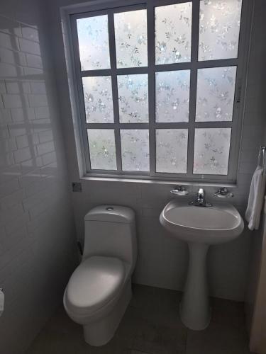 a bathroom with a toilet and a sink and a window at Milenio III B&B in Querétaro