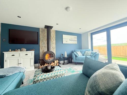 a blue living room with a couch and a tv at Seaside Getaway - Roebuck Cottage in Reighton