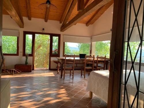 a dining room with a table and chairs and windows at Poetic glass house in the countryside in San Cipriano